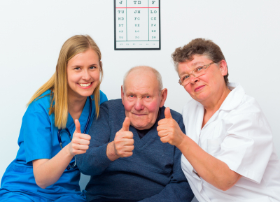 caregivers and senior man raising their thumb